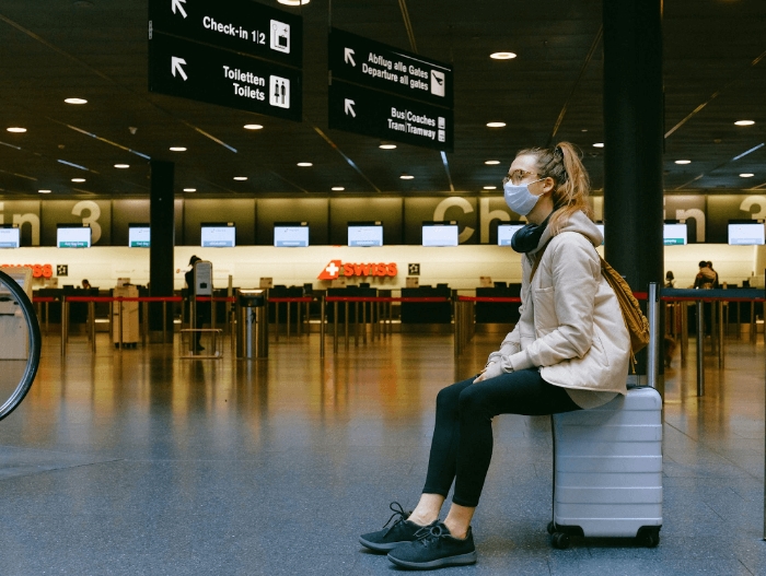 women sitting on luggage at airport