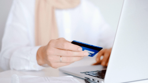 Person on computer holding credit card
