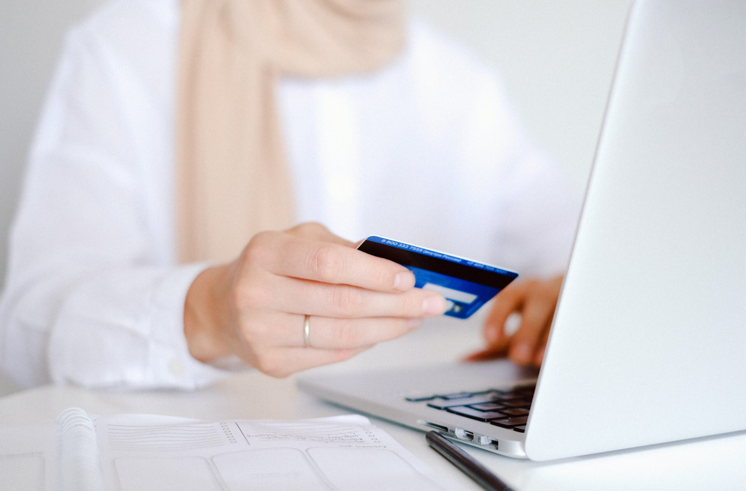 woman's hand holding a credit card while she sits in front of a computer
