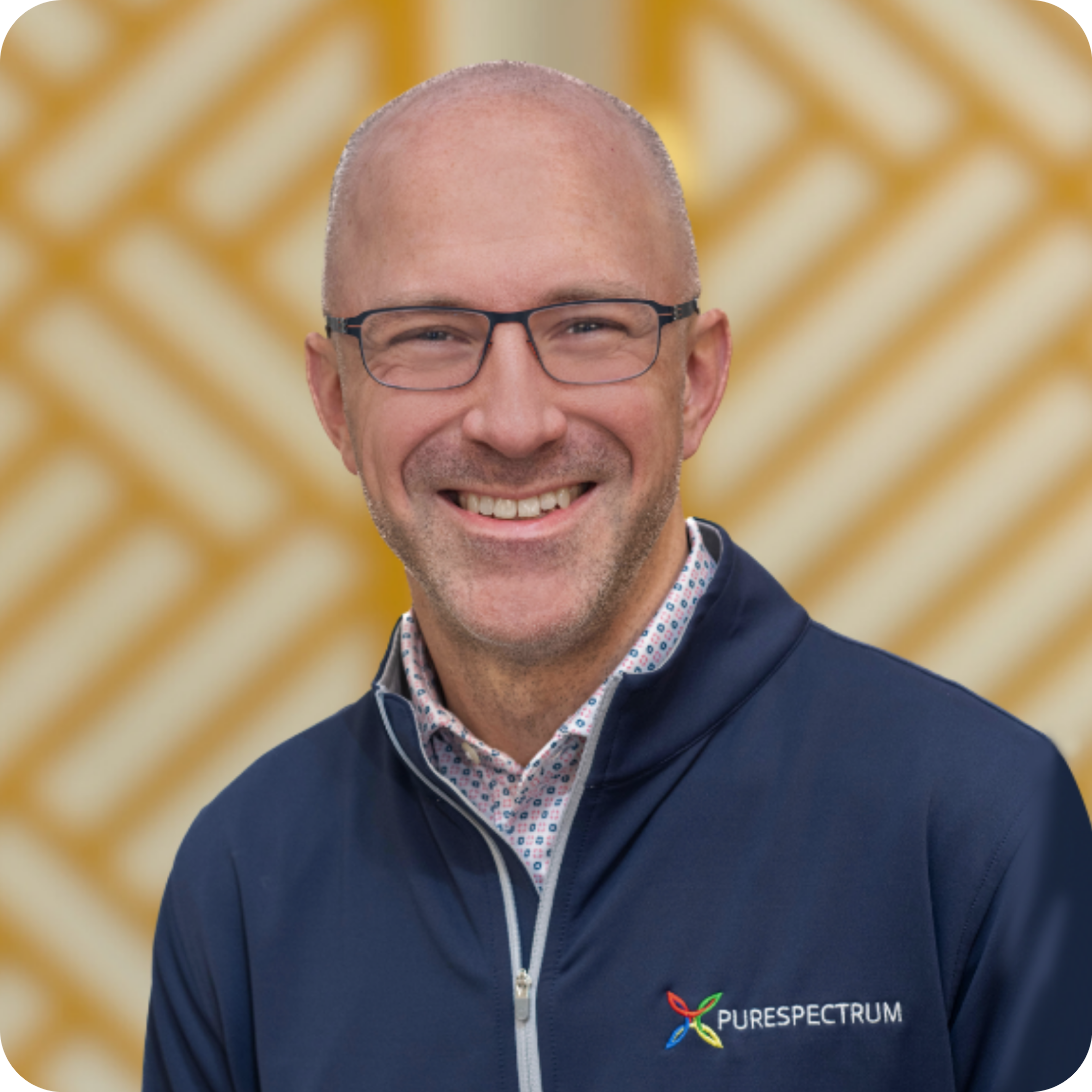 Mark-Menig Portrait of Estephanie Fuess, CMO of PureSpectrum, smiling in front of a patterned background.